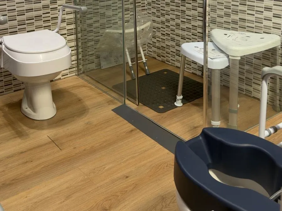 Bathroom set up in the Cocoon showroom: grab rails, raised toilet seat, walk-in shower with stool
