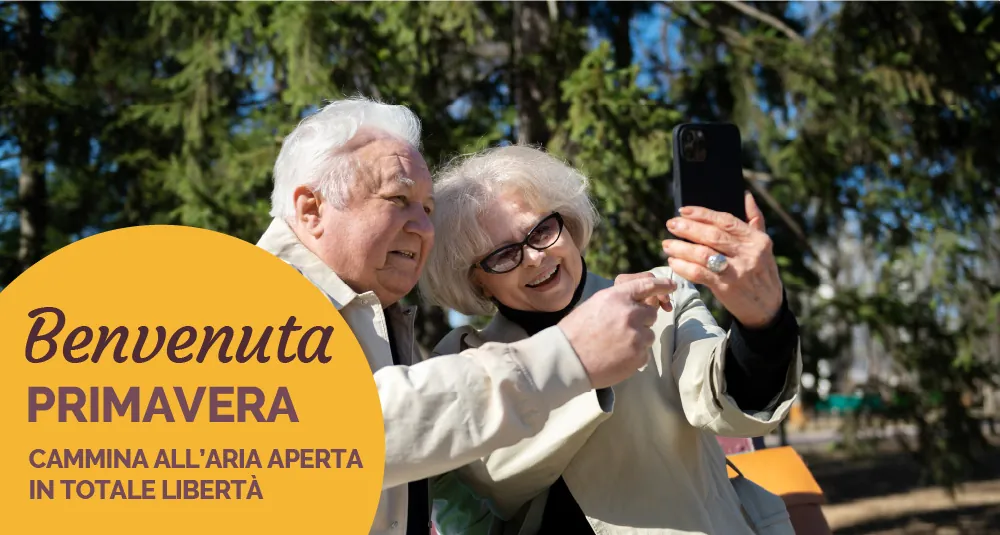 Coppia di anziani si scatta un selfie all’aperto, con la scritta «Benvenuta primavera: cammina all’aria aperta in totale libertà»