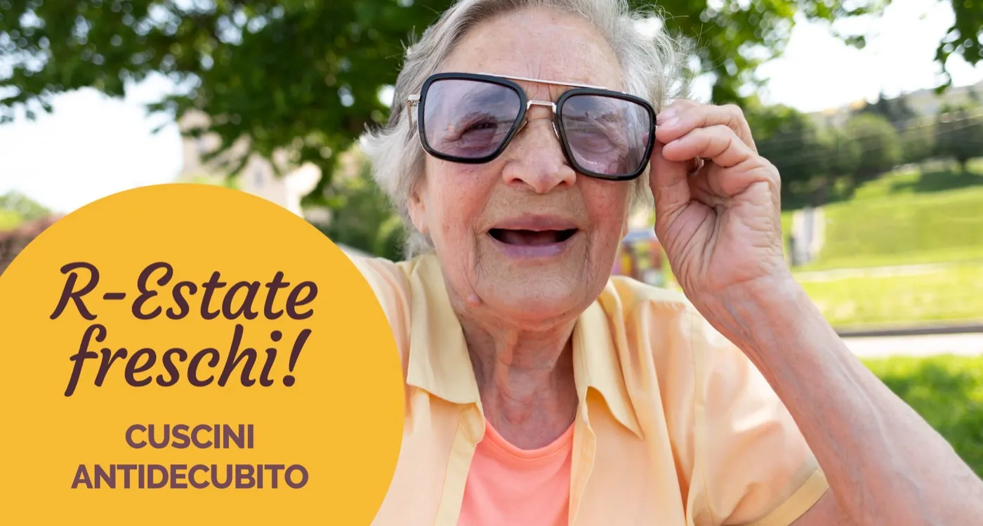 Signora anziana sorridente con gli occhiali da sole all’aperto, con la scritta «R-estate freschi! Cuscini antidecubito»