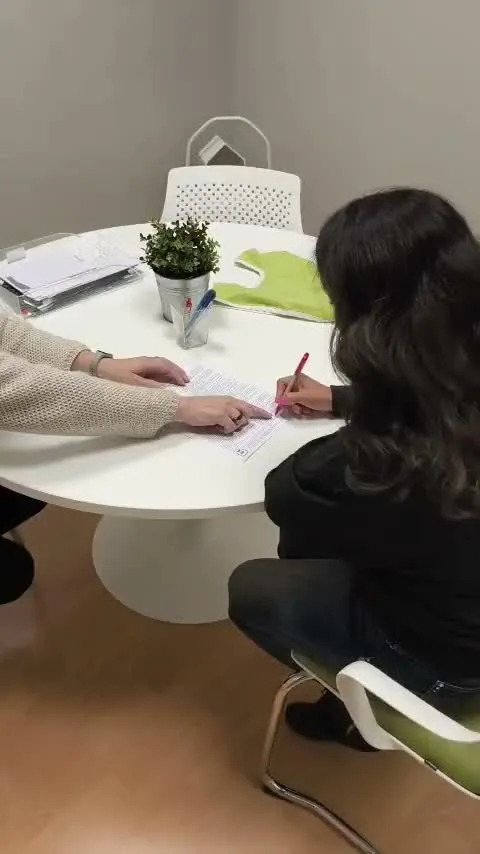 Two people signing documents at a table at the Cocoon office