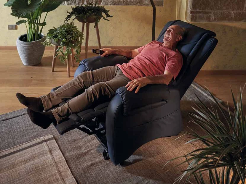 Un signore sdraiato su una poltrona relax lift reclinata, con le gambe sollevate e il telecomando in mano